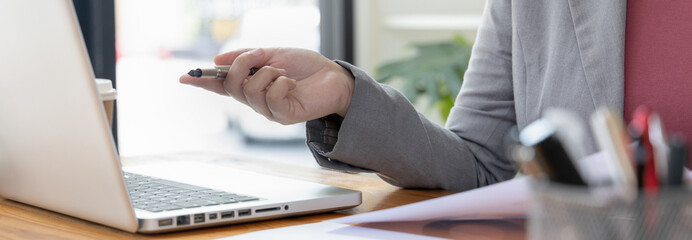 Business professionals are analyzing data using laptops to compute company annual revenue...