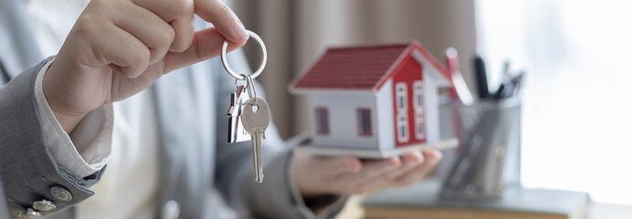 Sales manager or salesperson holds a demo house and has a home purchase contract with keys to...