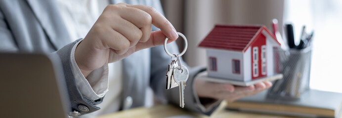 Sales manager or salesperson holds a demo house and has a home purchase contract with keys to...