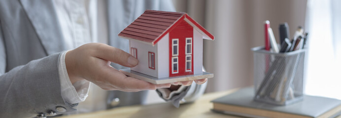 Sales manager or salesperson holds a demo house and has a home purchase contract with keys to...