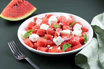 Salad of watermelon, feta cheese and mint on a green background, side view, close-up. Fruit salad.
