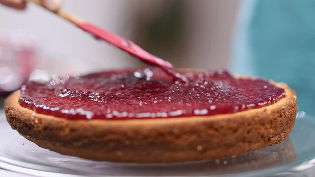 Spreading raspberry jam on Victoria Sponge cake.
