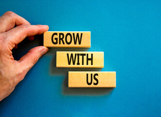 Grow with us symbol. Concept words Grow with us on wooden blocks on a beautiful blue table blue background. Businessman hand. Business, motivational and grow with us concept. Copy space.