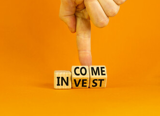 Invest or income symbol. Concept words Invest and Income on wooden cubes. Businessman hand. Beautiful orange table orange background. Business and invest or income concept. Copy space.