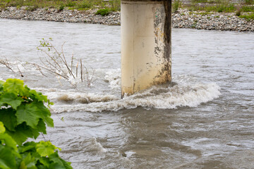 A raging river and tree branches stuck at the bridge support after heavy rains and a hurricane.