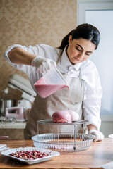 Central Asian Arabic woman pastry chef making Mirror Glaze Mousse cake. Female Middle East confectioner