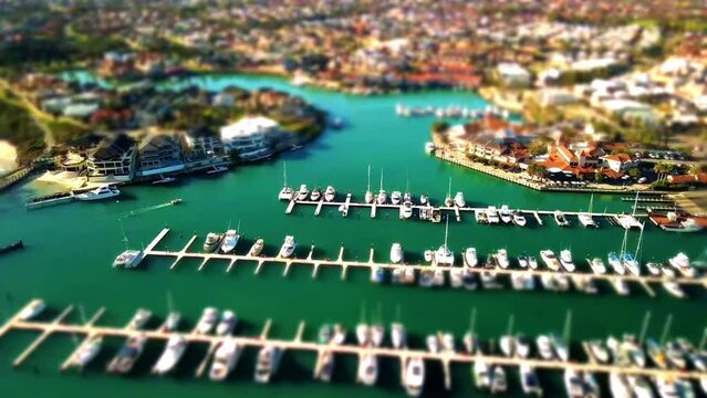 Aerial Miniature or tiltshift video of Mindarie Marina flying over the moored boats with a boat moving through the scene