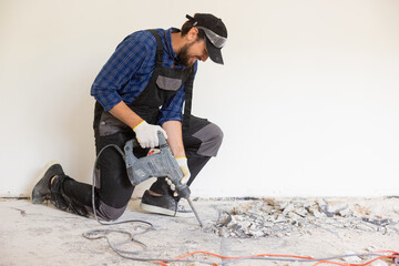 View of a construction worker using a hand-held demolition hammer and breaker to demolish walls to...