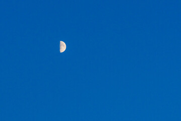 Small moon over blue glowing sky background.The Moon illuminated by the Sun.