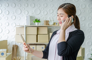 beautiful asian woman smile and check list product by tablet and talking with customer