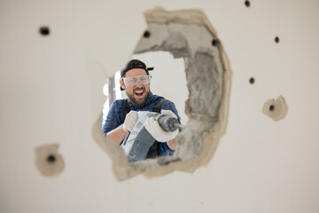 Demolition of an old house. Demolition of unnecessary walls with hand-held impact hammer. A view of...