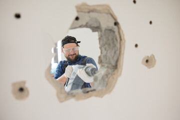 Demolition of an old house. Demolition of unnecessary walls with hand-held impact hammer. A view of...