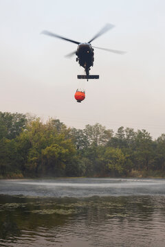 Military Helicopter Loading Water from a River for Firefighting a Large Scale Forest Fire Blaze in Slovenia