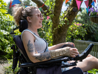 Woman in electric wheelchair sunbathing in back yard