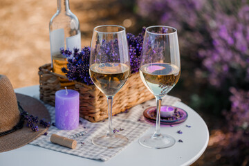 Two Glasses of white wine and bottle in a lavender field in Provance. Violet flowers on the background