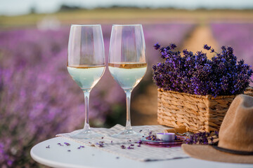 Two Glasses of white wine in a lavender field in Provance. Violet flowers on the background