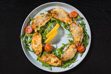 Cooked oysters with lemon, tomato and arugula