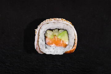 Roll with sesame seeds, eel, rice, nori, avocado, salmon