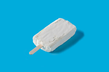 Briquette of white creamy ice cream on a stick on a blue background