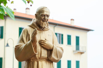 Piombino, Livorno, Italy - 2022, May 27: Padre Pio (Father Pio) golden statue, in the act of...