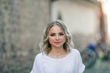 Young beautiful blue-eyed blonde in the center of a European city. Portrait of a stylish model in casual clothes. Happy youth.