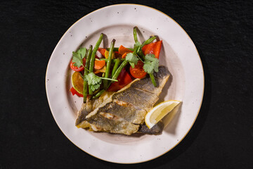 Fried fish with pods, lemon, parsley, tomato and mushroom