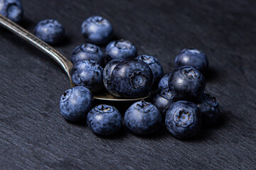 Blueberries on a black background. A teaspoon full of blueberries. Useful and tasty berry.