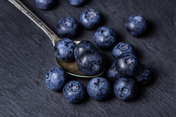 Blueberries on a black background. A teaspoon full of blueberries. Useful and tasty berry.