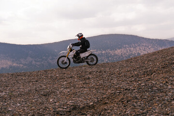 Motorcyclist riding off-road motorcycle on gravel rocky slope in mountains hills © Annatamila
