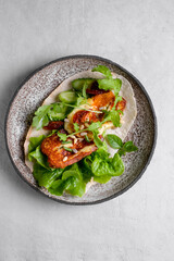 Plate with fresh vegetarian tacos billed by plants, arugula, cheese, basil and strawberry.
