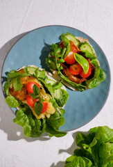 Plate with fresh vegetarian tacos billed by plants, arugula, cheese, basil and strawberry.