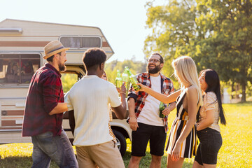 A group of cheerful friends set off on an RV trip. The students have arrived at their destination and are enjoying their time together. They are drinking beer and laughing