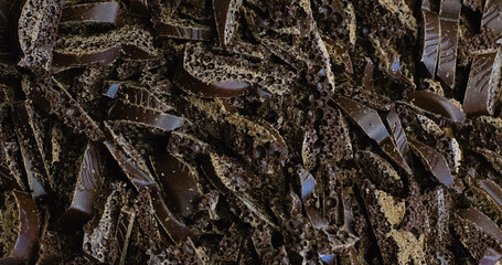 Chocolate background with copy space, pieces of porous chocolate, dark chocolate shavings close-up macro.