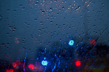 Light of the traffic and car on a rainy night through the windshield