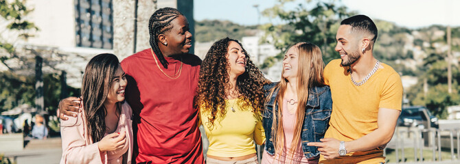 Multiracial young people walking happily on the street - Guys and girls having fun together -...