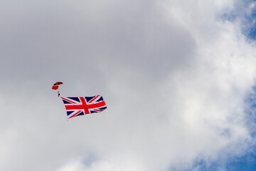 A man with the Union Jack attached to his leg parachuting against the cloudy sky