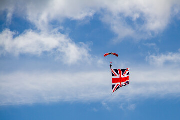 Daredevil stunt parachutist in the blue sky with the Great Britain flg attached