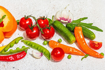 Assorted fresh vegetables and spices on light plaster background. Ripe yellow pepper, tomato, pea