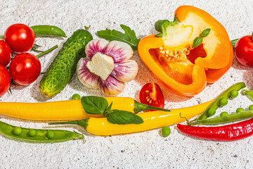 Assorted fresh vegetables and spices on light plaster background. Ripe yellow pepper, tomato, pea