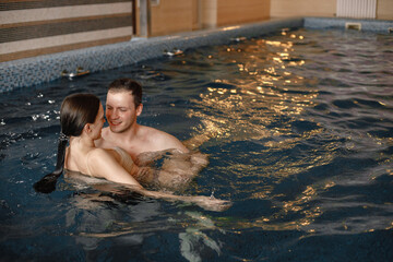 Cute couple swimming together in indoors swimming pool