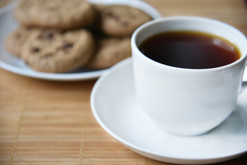 Tea pair and oatmeal cookies with chocolate on a mat. Delicious breakfast with tea and sweet cookies.