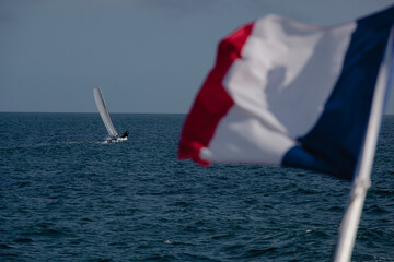 The French flag flies in the wind in front of the sea. The French flag, blue white red, is hung on...