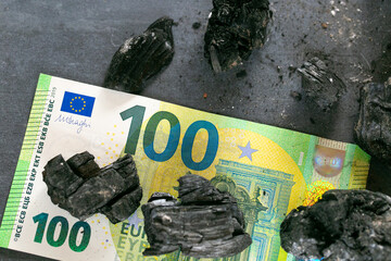 Coal cost in Europe.Charcoal and one hundred euro bills close-up.Coal industry in the European Union.Buying and selling coal in the countries of the European Union.