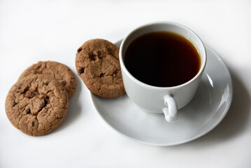 Tea pair and oatmeal cookies with chocolate on a white background. Delicious lunch with tea and sweet cookies. Porcelain tea set with a hot drink.