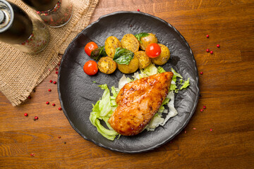 Grilled chicken Breasts with mini potatoes on black plate