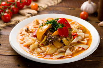 Lagman asian soup with beef and noodles on wooden table