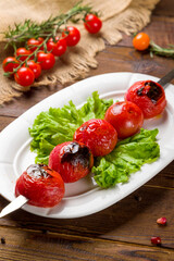 Skewers tomato kebab on white plate on wooden table