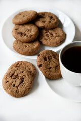 Tea pair and oatmeal cookies with chocolate on a white background. Delicious lunch with tea and sweet cookies. Porcelain tea set with a hot drink.