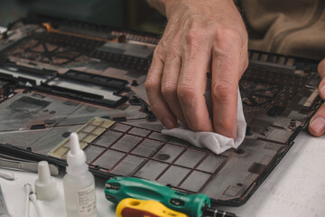 cleaning the back cover of the laptop from dirt, dust. updating computer components. repair and maintenance of computers. the concept of repair, modernization and technology. close-up.