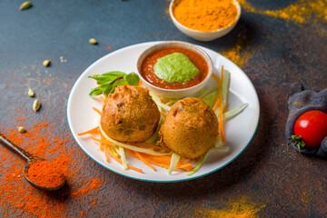 Indian samosa with vegetables, alu vonda with tomato mint sauce on dark blue table